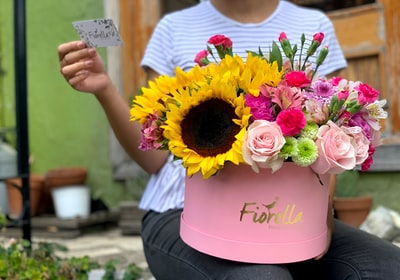女人腿上的粉红色花瓶中的各色花瓣花
